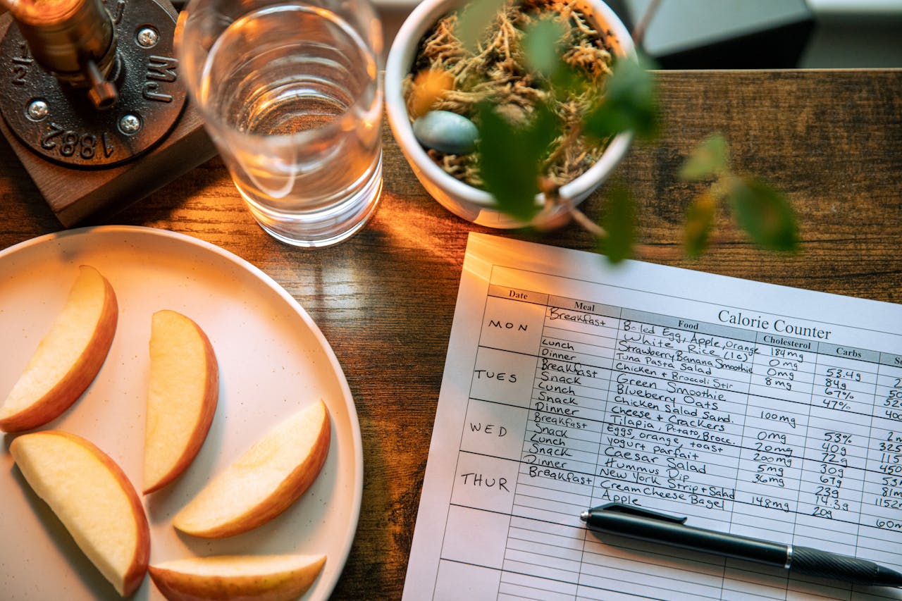 Mastering the First Impression: Your intriguing post title goes here Top view of apple slices, water, and a calorie counter sheet on a wooden table promoting a healthy lifestyle.